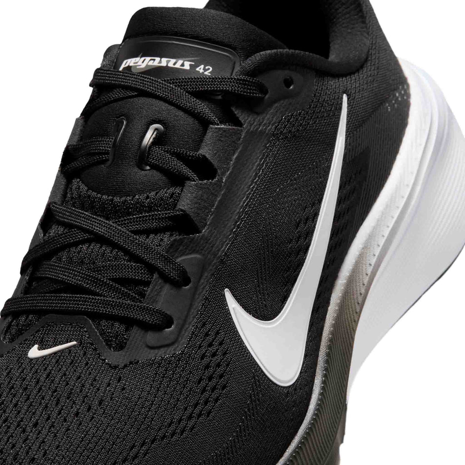 Close-up view of the upper of the left shoe from a pair of Nike Women's Pegasus 42 Road Running Shoes in the Black/White-Iron Grey colourway.