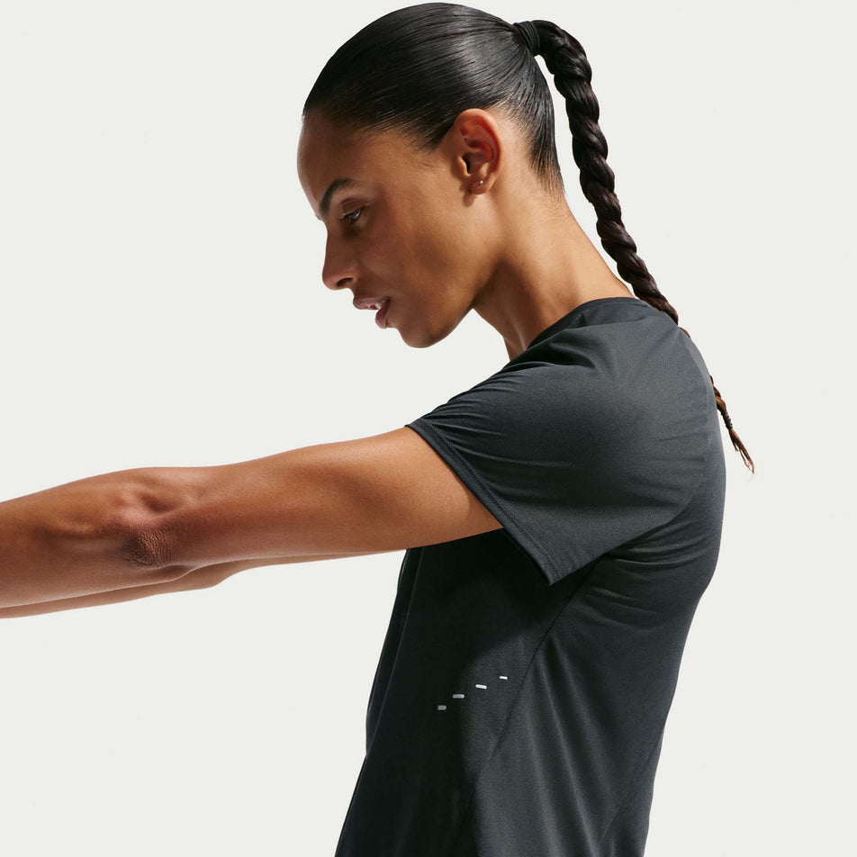Side view of a model wearing the Nike Women's Swift Breathe Dri-FIT Short-Sleeve Running Top in the Black/Photon Dust/White/Reflective Silver colourway.