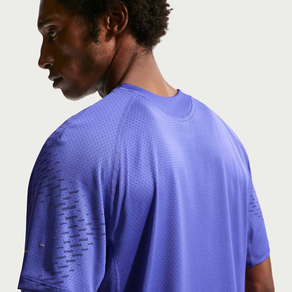 Angled view of a model wearing the Nike Men's Stride Plus Dri-FIT ADV Short-Sleeve Running Top in the Lapis/Deep Royal Blue/Reflective Silver colourway.