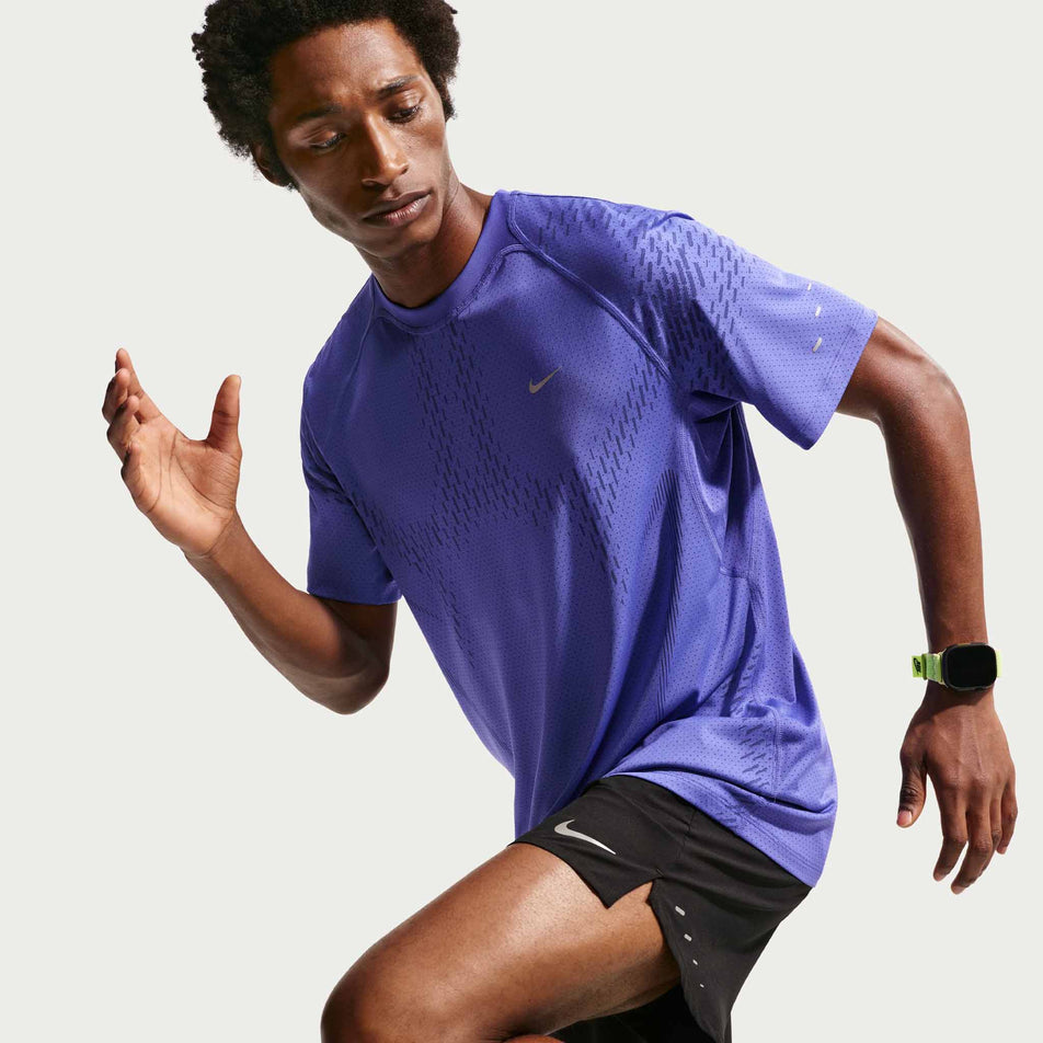 Angled view of a model wearing the Nike Men's Stride Plus Dri-FIT ADV Short-Sleeve Running Top in the Lapis/Deep Royal Blue/Reflective Silver colourway.