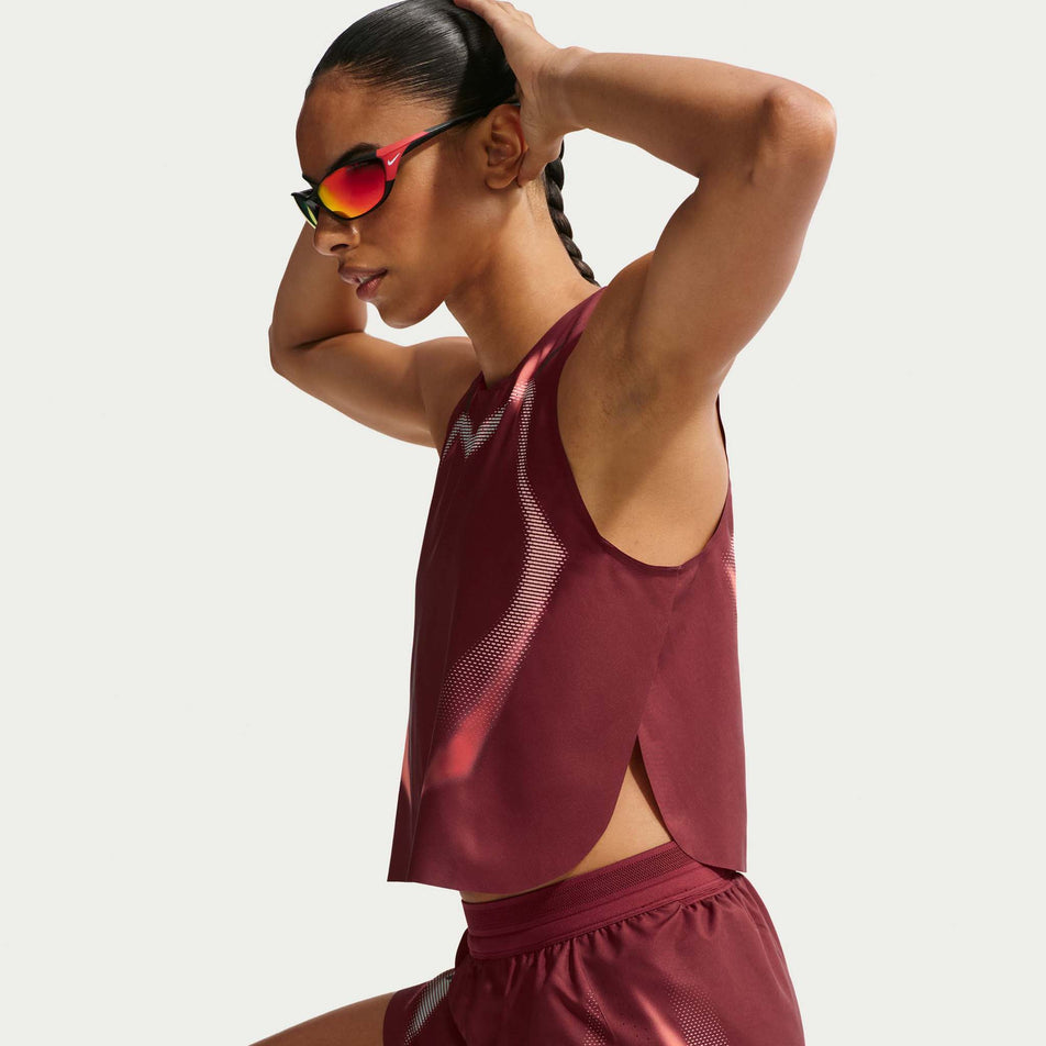 Side view of a model wearing the Nike Women's AeroSwift Dri-FIT ADV Cropped Running Tank Top in the Team Red/Black/Black colourway.