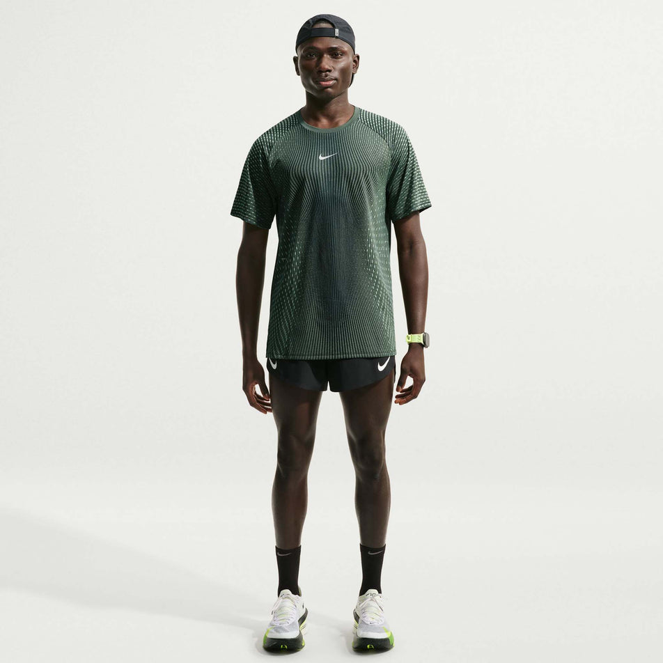 Front view of a model wearing the Nike Men's Stride Aero-FIT Short-Sleeve Running Top in the Black/Light Green Spark/Reflective Silver colourway.