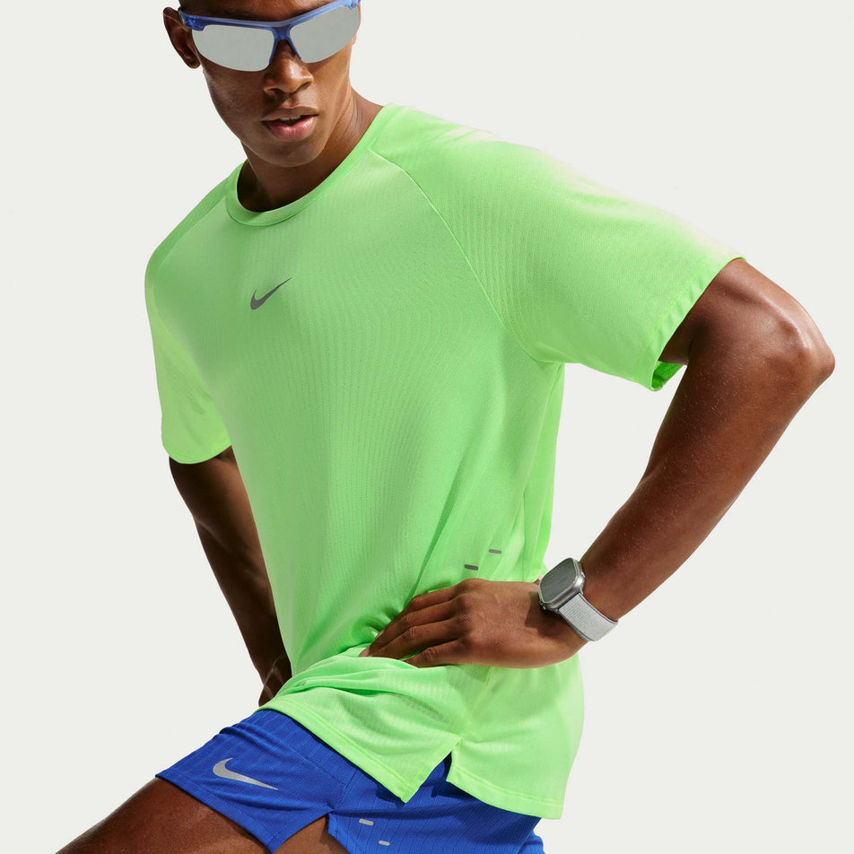 Angled view of a model wearing the Nike Men's Stride Aero-FIT Short-Sleeve Running Top in the Volt/Light Silver/Reflective Silvern colourway.