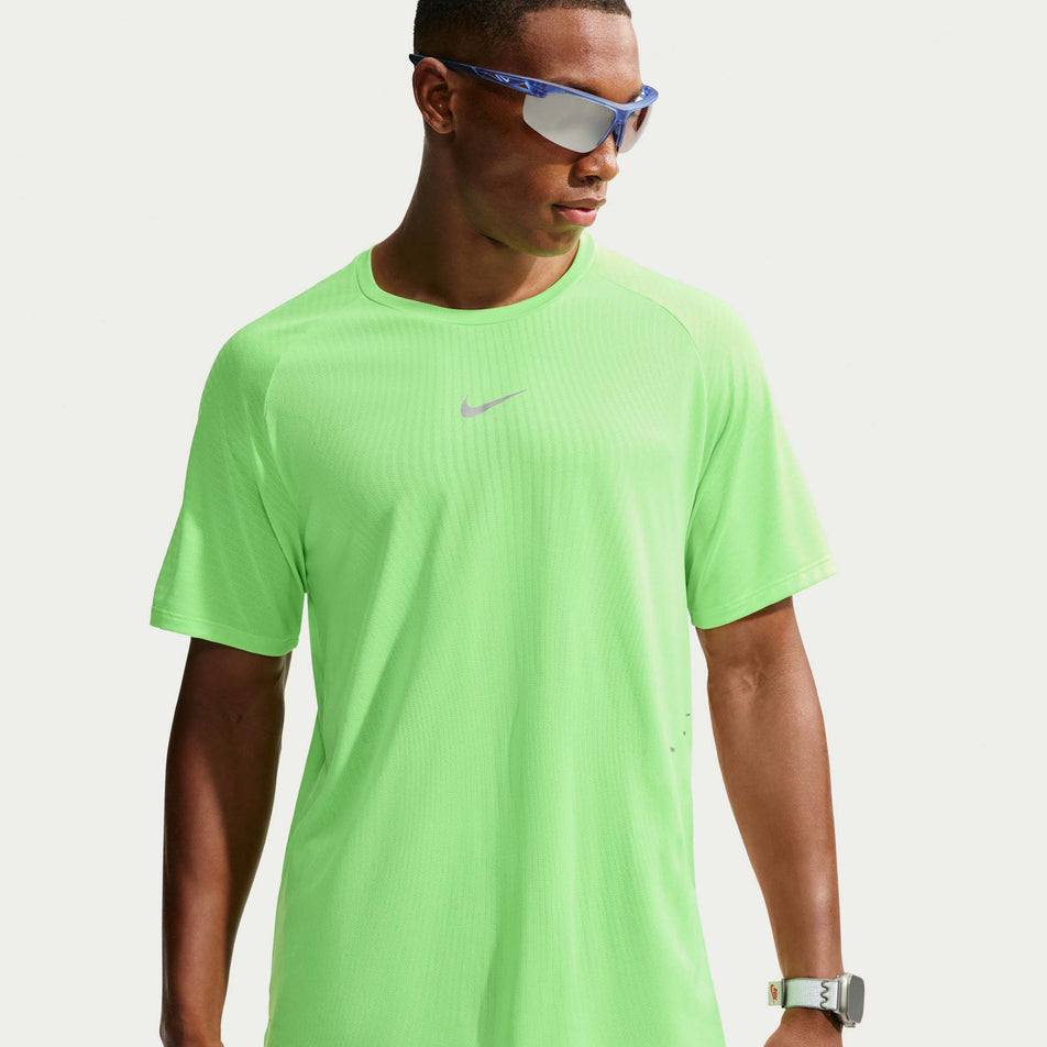 Front view of a model wearing the Nike Men's Stride Aero-FIT Short-Sleeve Running Top in the Volt/Light Silver/Reflective Silvern colourway.