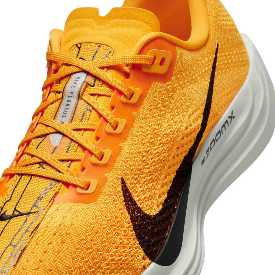 Close up of the upper of the left shoe from a pair of Nike Men's Pegasus Plus LV8 Road Running Shoes in the University Gold/Black-Laser Orange Sail colourway. (8684355584162)