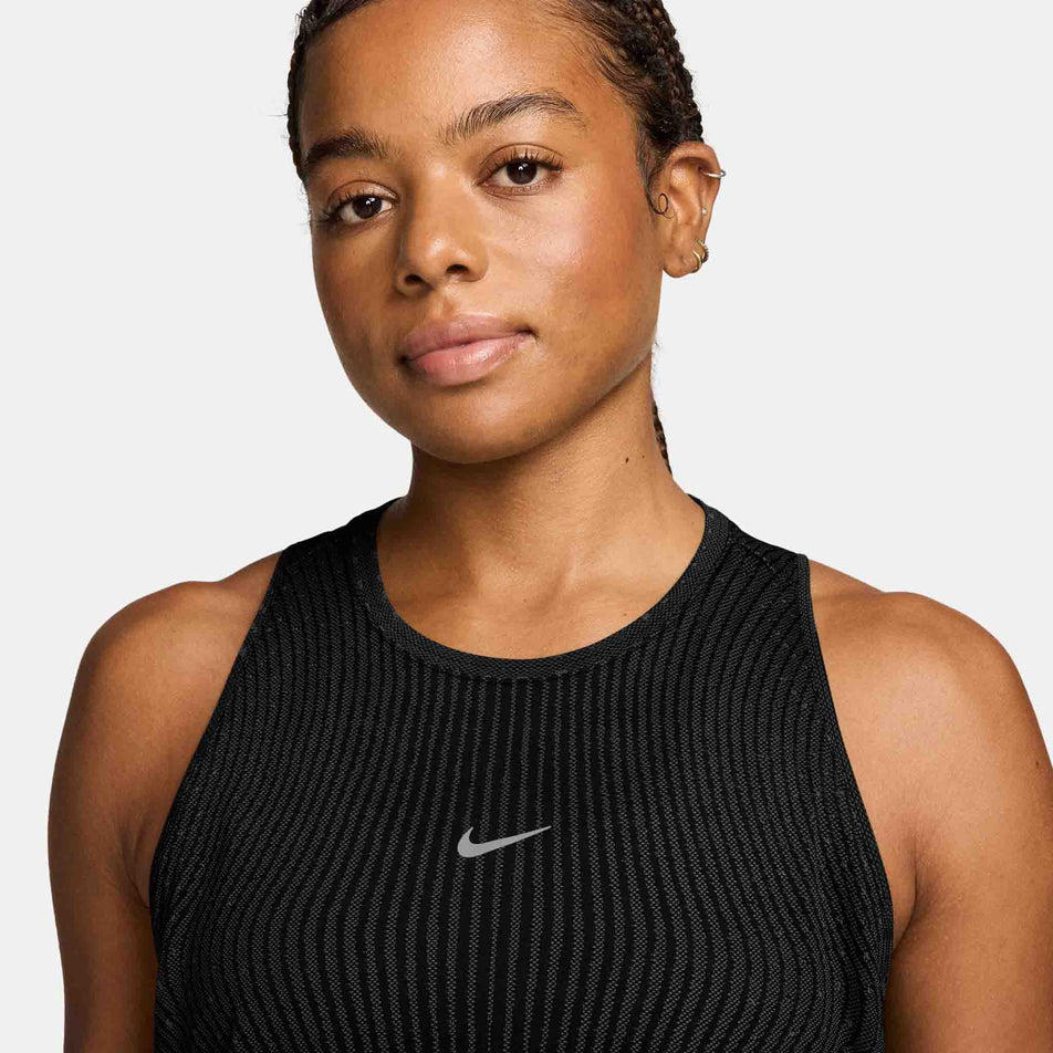 Front view of a model wearing the Nike Women's Swift Aero-FIT Running Tank Top in the Black/Light Green Spark/Reflective Silver colourway.