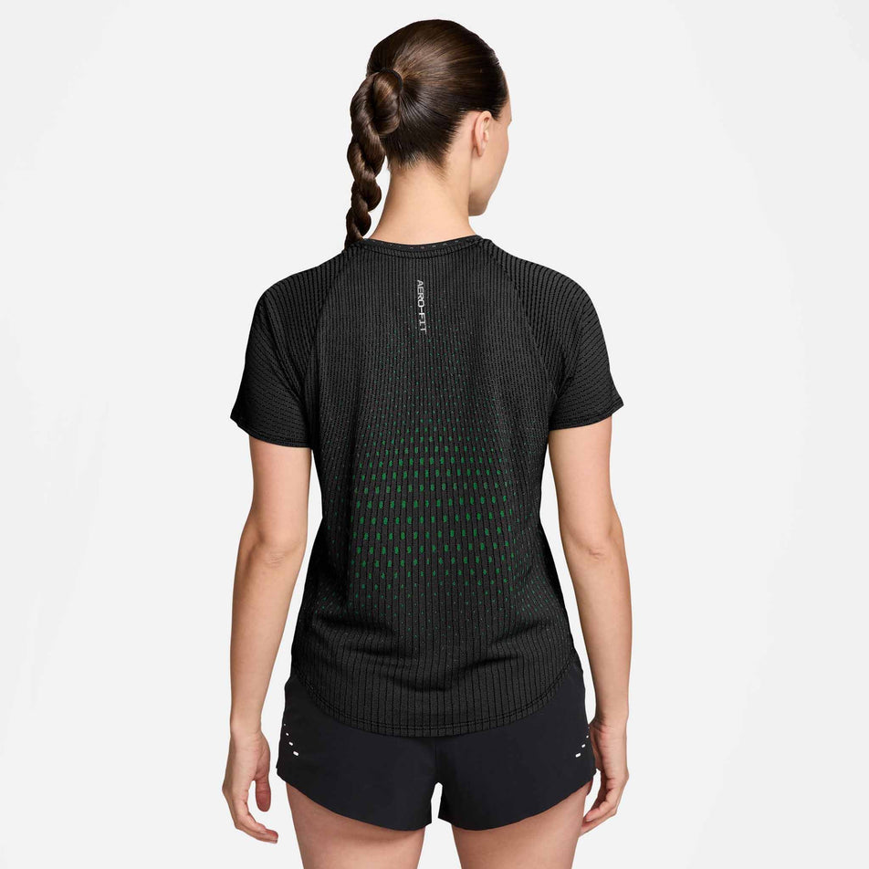 Back view of a model wearing the Nike Women's Swift Aero-FIT Short-Sleeve Running Top in the Black/Green colourway.