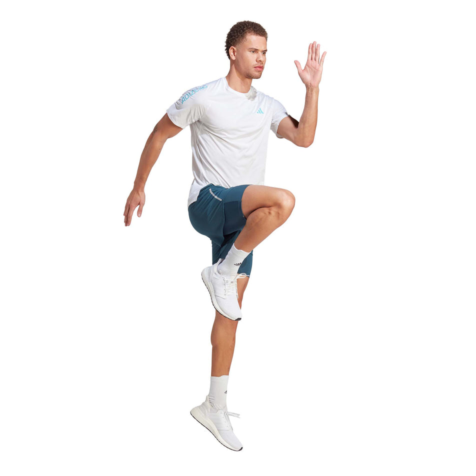 Angled side view of a model wearing a pair of adidas Men's Designed 4 Running 2-in-1 Shorts in the Arctic Night colourway. Model is in a running pose. (8005321064610)