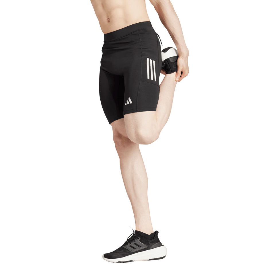 Side view of a model wearing the adidas Men's Own The Run Short Tights in the Black colourway. (8751020671138)