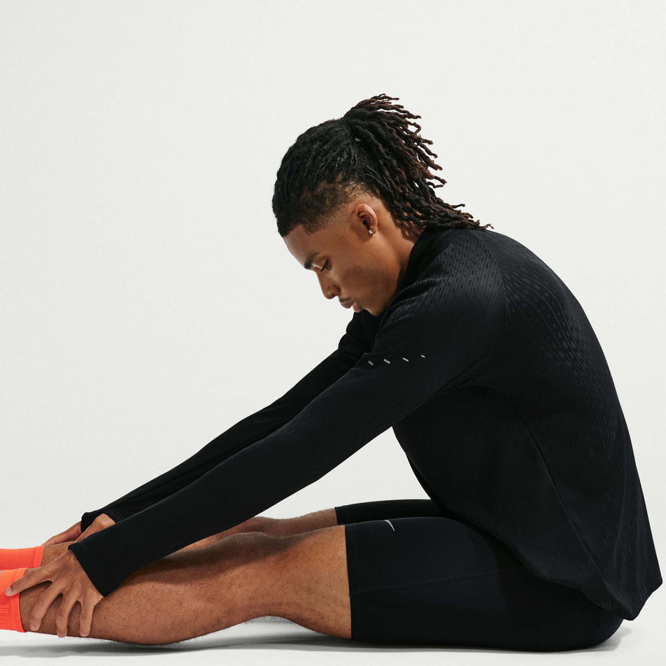 Angled view of a model wearing the Nike Men's Stride Aero-FIT 1/2-Zip Mid Layer in the Black/Reflective Silver colourway.