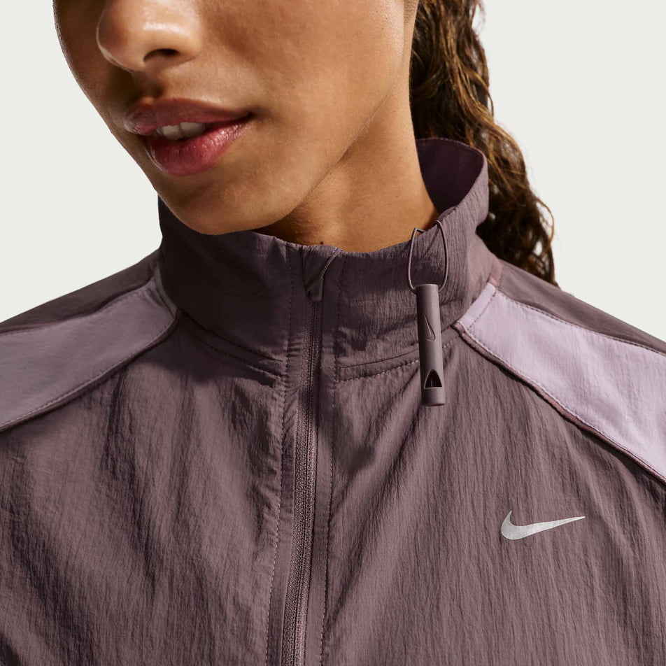 The whistle on the collar of the Nike Women's Swift Repel UV Protection Running Jacket in the Tattoo/Light Violet Ore/Reflective Silver colourway.