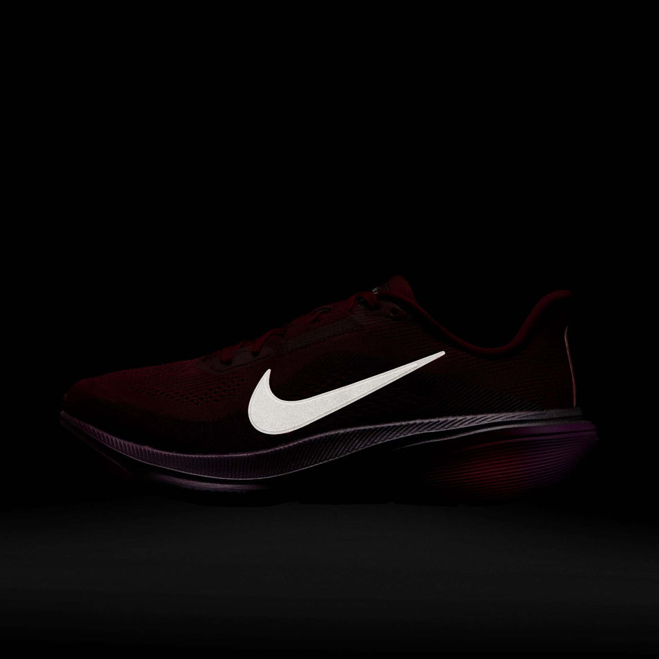 The reflective swoosh on the lateral side of the left shoe from a pair of Nike Women's Pegasus 42 SE Road Running Shoes in the Team Red/Barely Green-Atomic Pink colourway.