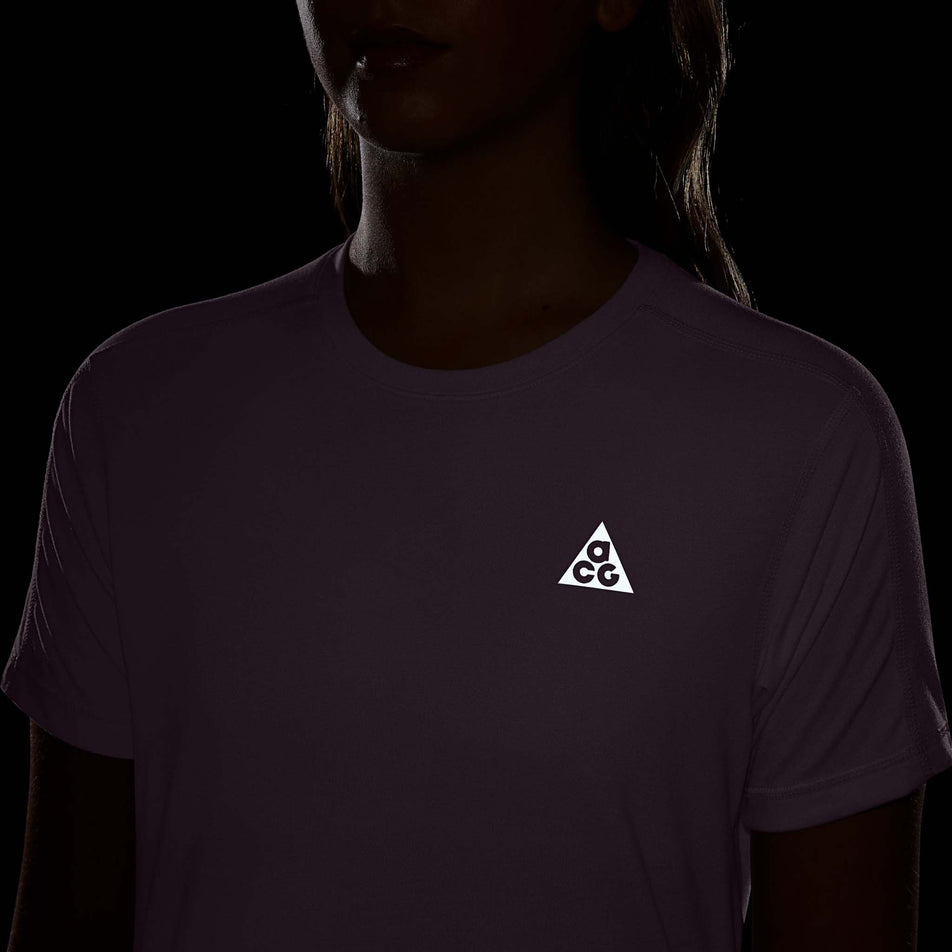 The reflective ACG branding on the front of the Nike Women's ACG Dri-FIT Short-Sleeve Trail Running Top in the Violet Dust/Summit White colourway.