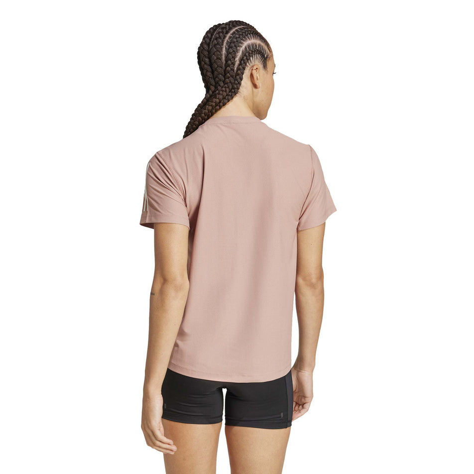 Back view of a model wearing the adidas Women's Own The Run Base Tee in the Warm Clay colourway. (8567456235682)