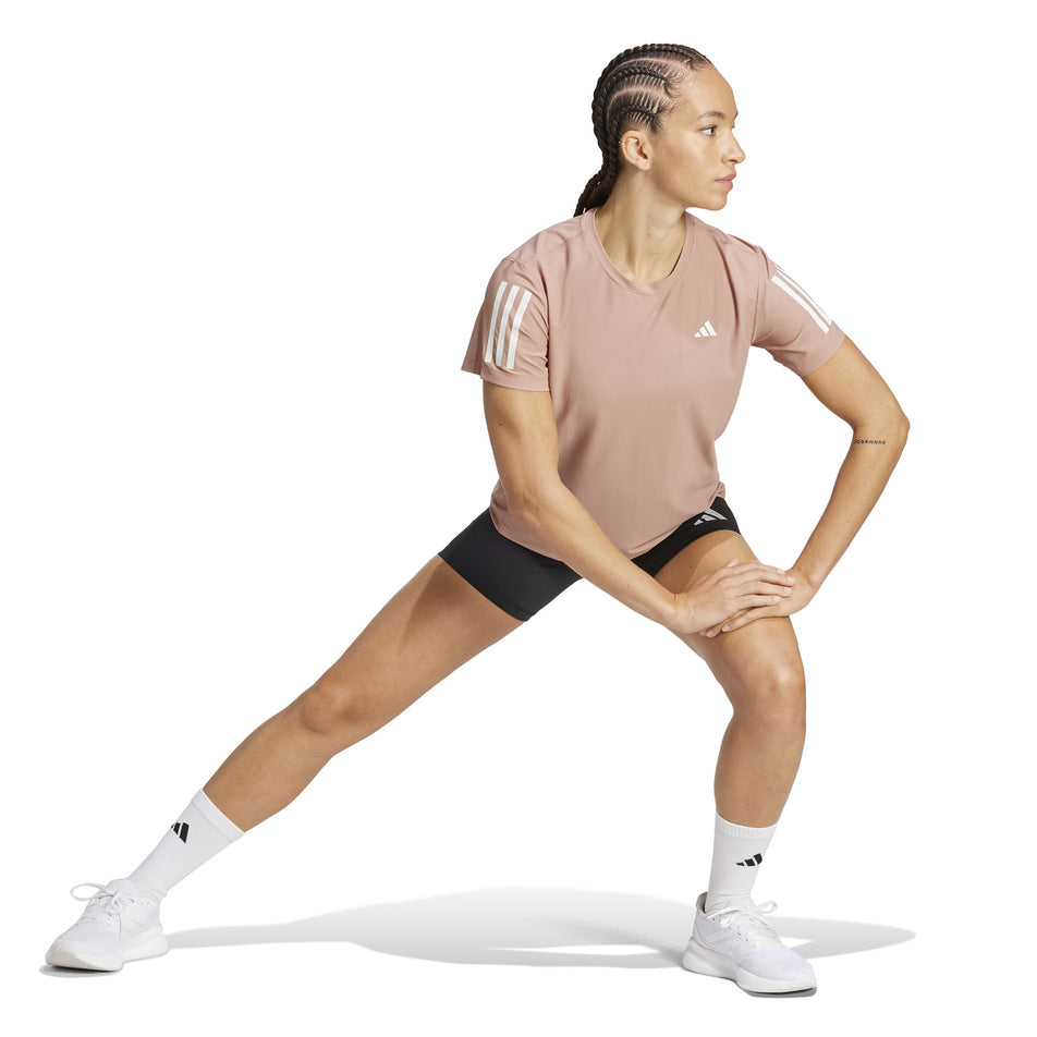 Front view of a model wearing the adidas Women's Own The Run Base Tee in the Warm Clay colourway. (8567456235682)
