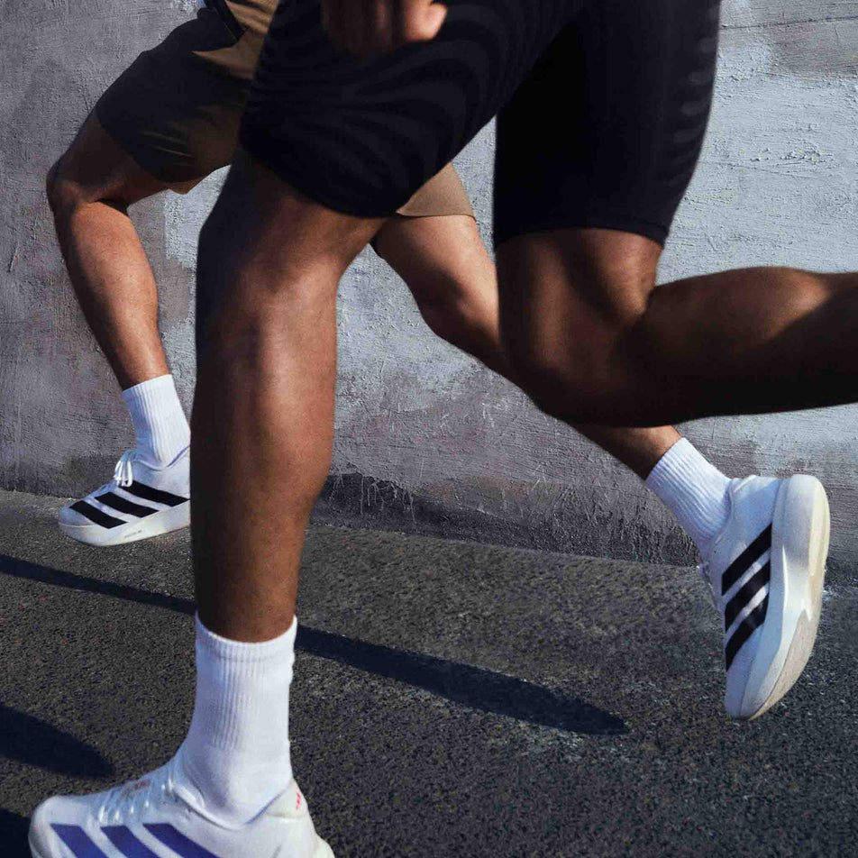 Models running in the adidas Men's Adizero EVO SL Running Shoes in the Ftwr White/Core Black/Ftwr White colourway.
