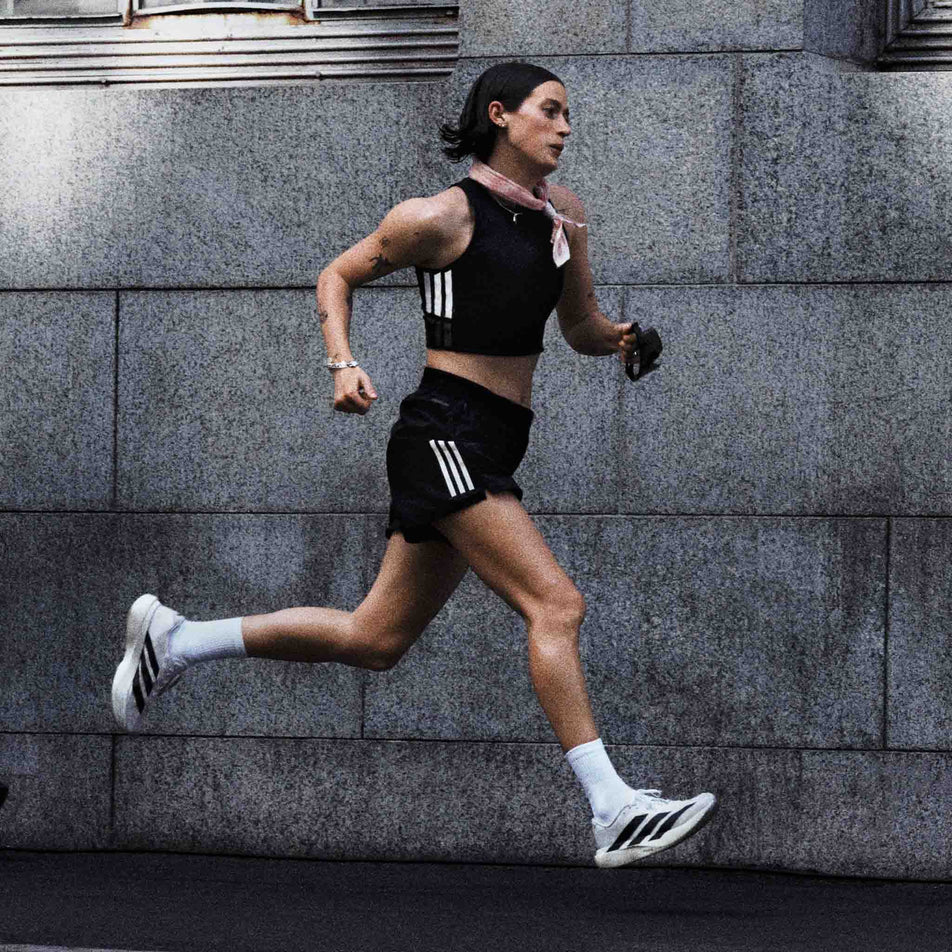 A model running in a pair of adidas Women's Adizero EVO SL Running Shoes in the Ftwr White/Core Black/Ftwr White colourway.