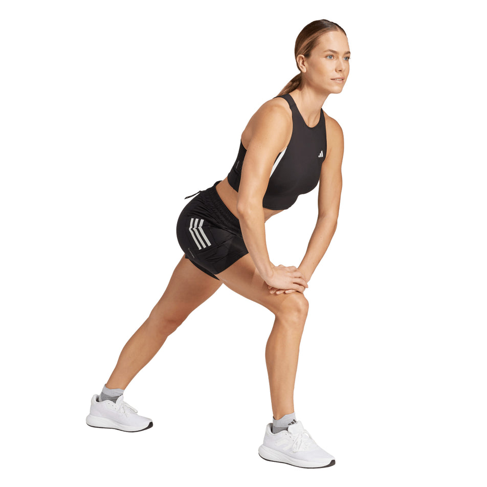 Side view of a model wearing the adidas Women's Own The Run Base 2in1 Short in the Black colourway.k (8665239847074)