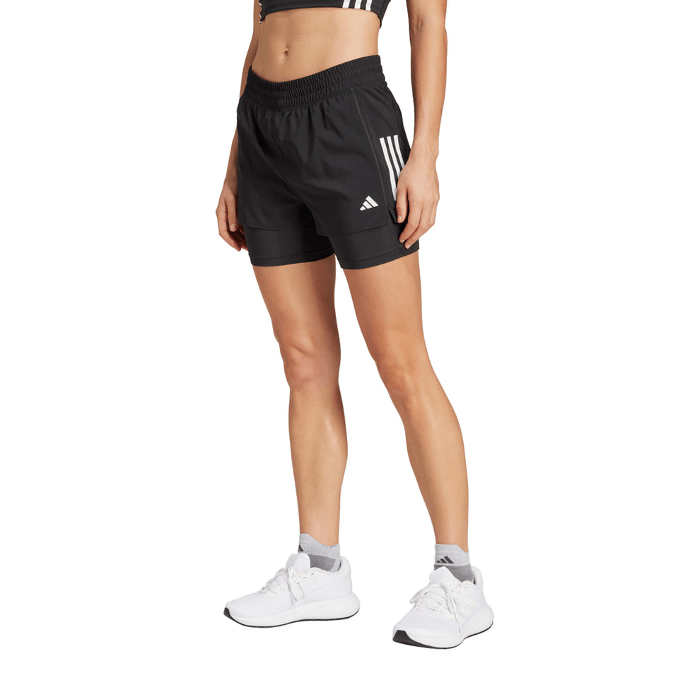 Front view of a model wearing the adidas Women's Own The Run Base 2in1 Short in the Black colourway. (8665239847074)