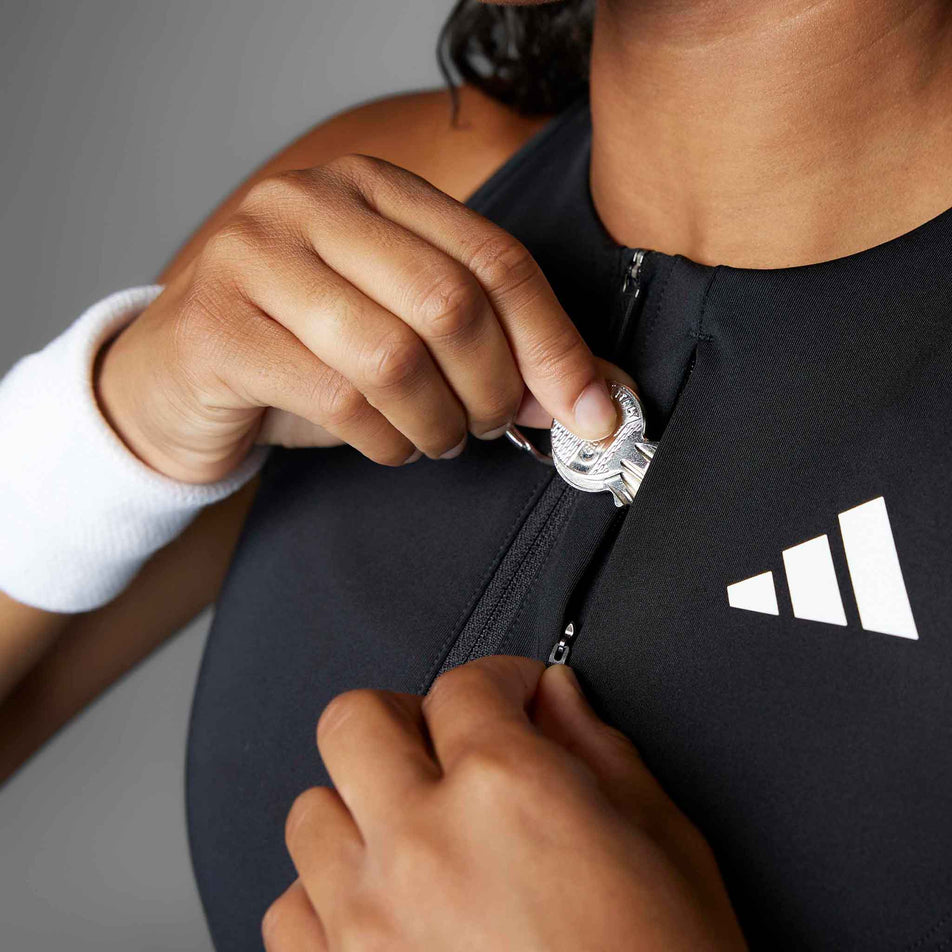 A model demonstrating the zip pocket on the adidas Women's Adizero Running Gel Pocket Crop in the Black colourway.