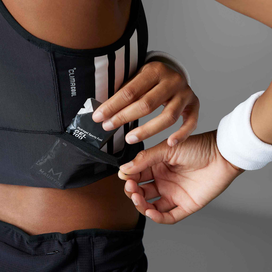 A model demonstrating the stash pocket on the adidas Women's Adizero Running Gel Pocket Crop in the Black colourway.