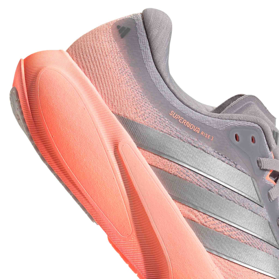 Close-up view of the rearfoot section of the right shoe from a pair of adidas Women's Supernova Rise 3 Running Shoes in the Clear Orange/Silver met./Glory Grey colourway.