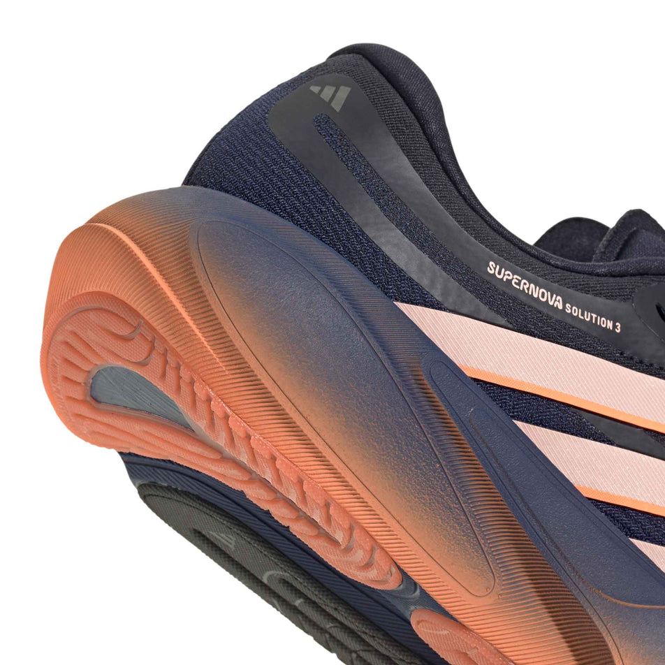 Close-up view of the rearfoot section of the right shoe from a pair of adidas Women's Supernova Solution 3 Running Shoes in the Dark Blue/Clear Orange/Beam Orange colourway.