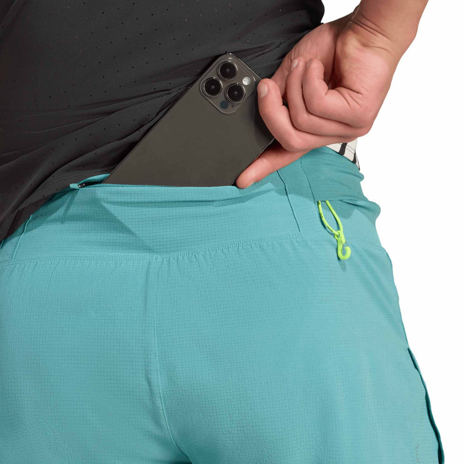 A model demonstrating the zip pocket on the back of the adidas Men's Adizero Gel Short in the Powder Teal colourway. (8663030333602)
