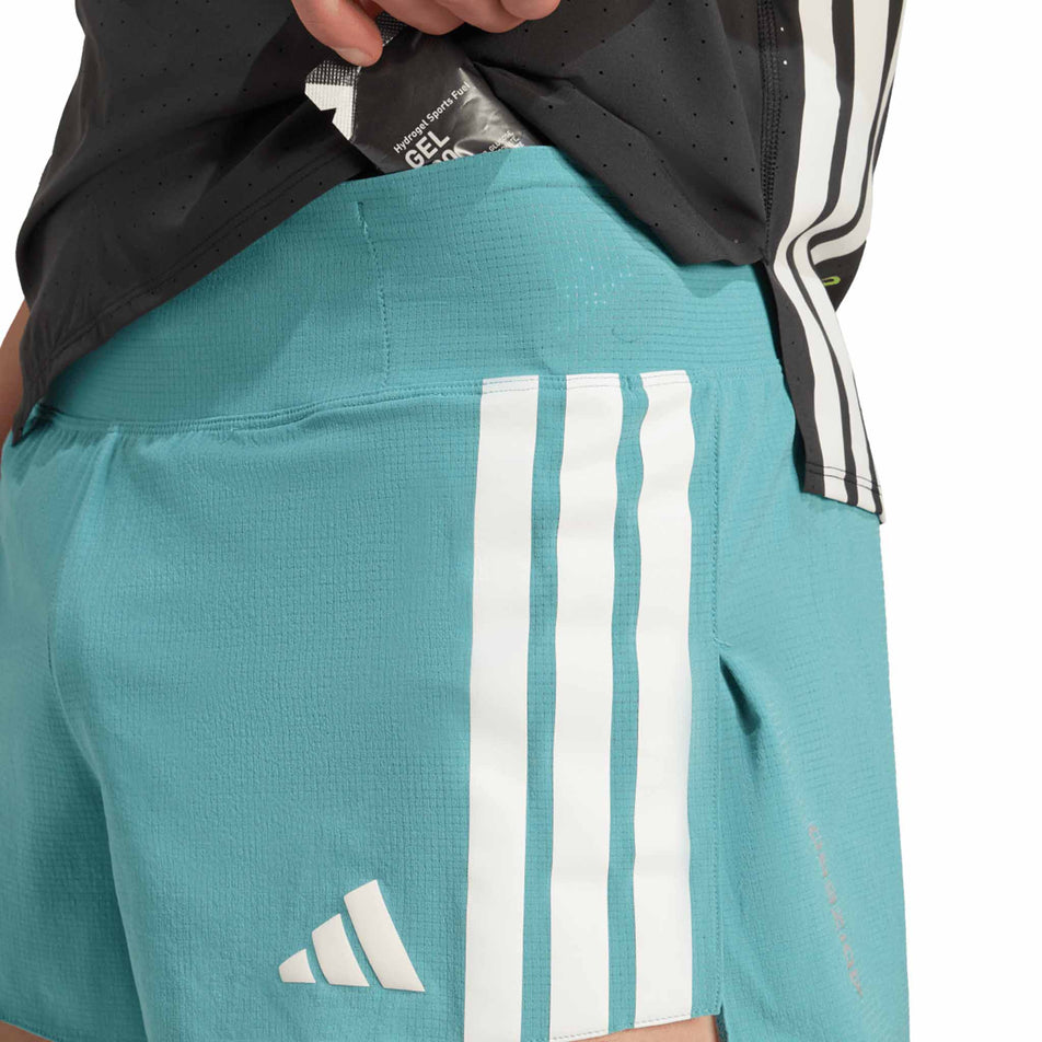 A model demonstrating the storage on the front of the adidas Men's Adizero Gel Short in the Powder Teal colourway. (8663030333602)