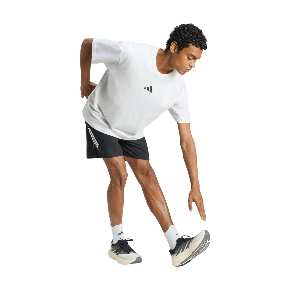 Angled view of a model wearing the adidas Unisex Running Category Graphic T-Shirt in the White colourway.