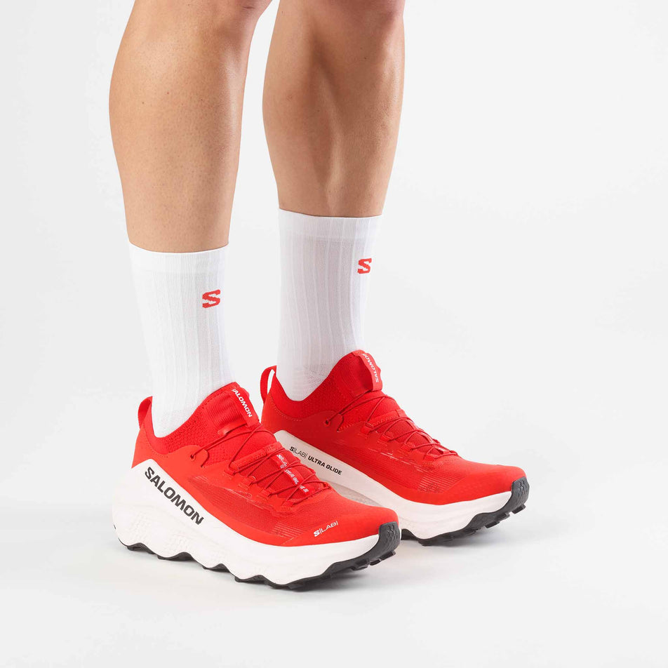 A model wearing a pair of Salomon Unisex S/Lab Ultra Glide 2 Trail Running Shoes in the Fiery Red/Fiery Red colourway.
