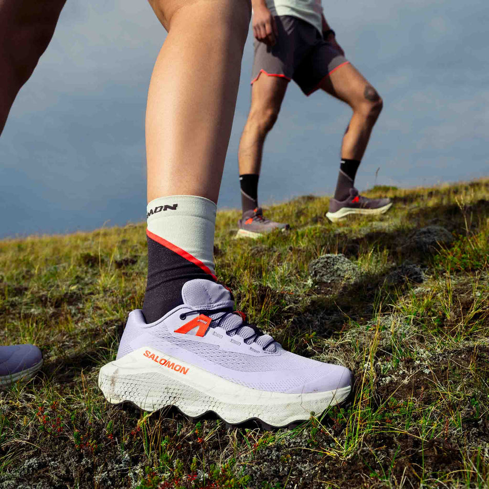 A model wearing a pair of Salomon Women's Ultra Glide 3 Running Shoes in the Cosmic Sky/Icicle/Neon Flame colourway. (8576019497122)