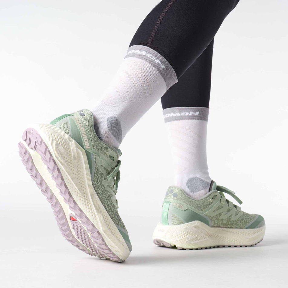 Side view of a model wearing a pair of Salomon Women's Aero Glide 3 GRVL Running Shoes in the Sea Foam/Vanilla Ice/Nirvana colourway. (8644619731106)