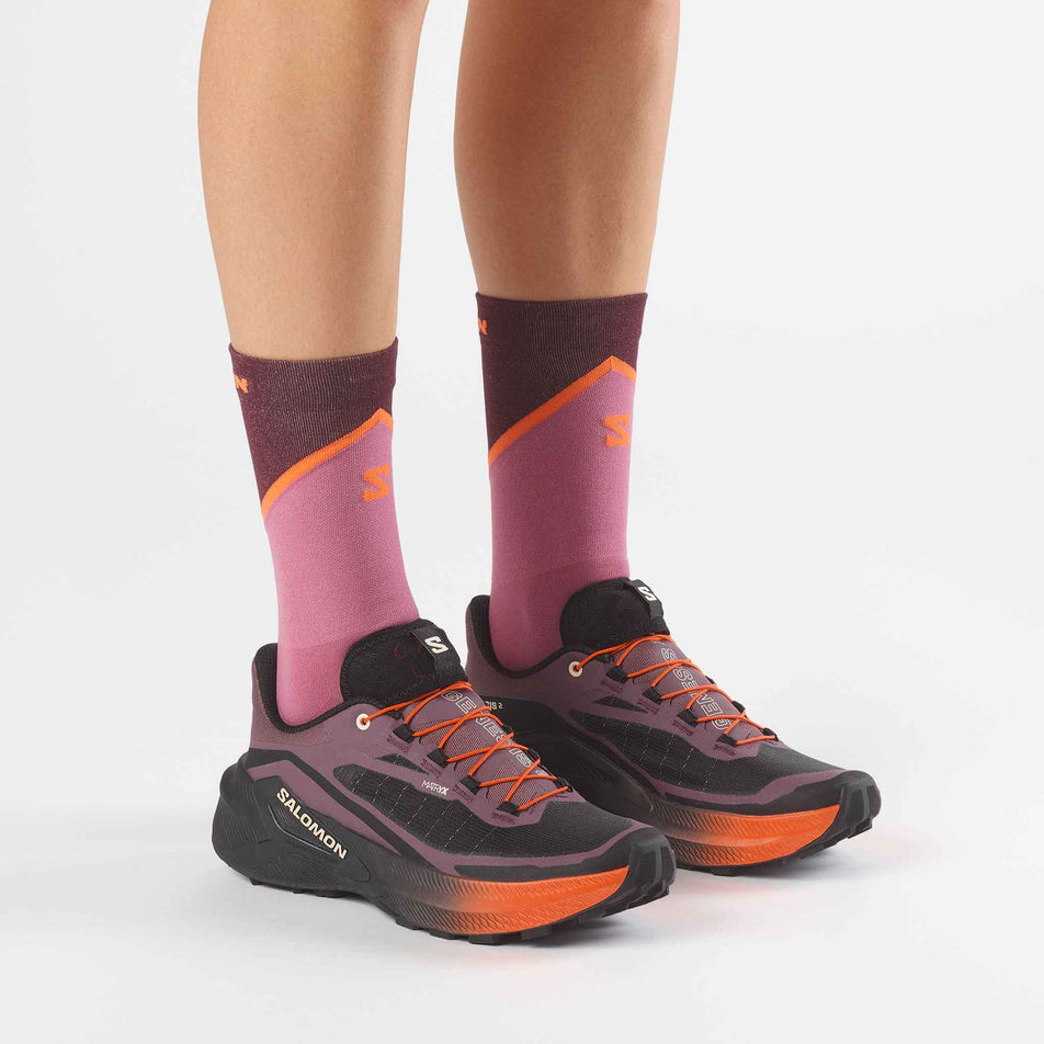 A model wearing a pair of Salomon Women's Genesis 2 Trail Running Shoes in the Huckleberry/Black colourway.