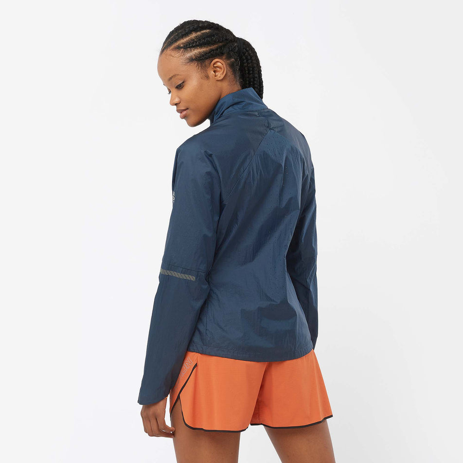 Back view of a model wearing a Salomon Women's Sense Flow Jacket in the Carbon/Carbon colourway. Model is also wearing Salomon running shorts. (8071093649570)
