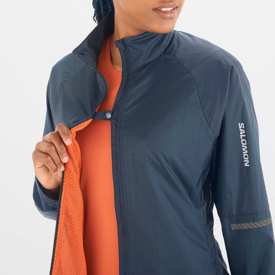 A model demonstrating that a button clip at the chest section of a Salomon Sense Flow Jacket can be used to keep the jacket in place while it is unzipped. (8071093649570)