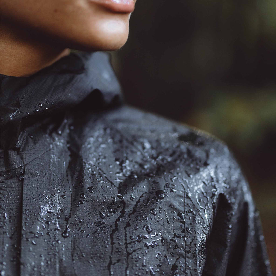 A model wearing a Salomon Bonatti Waterproof Shell Jacket in the Deep Black colourway. Beads of water are sitting on the jacket. (8464141320354)