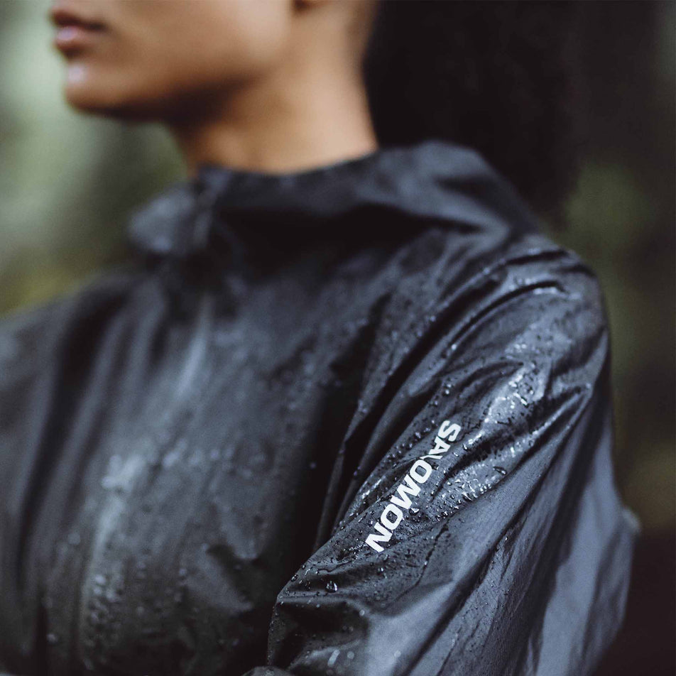 A model wearing a Salomon Bonatti Waterproof Shell Jacket in the Deep Black colourway. Beads of water are sitting on the jacket. (8464141320354)