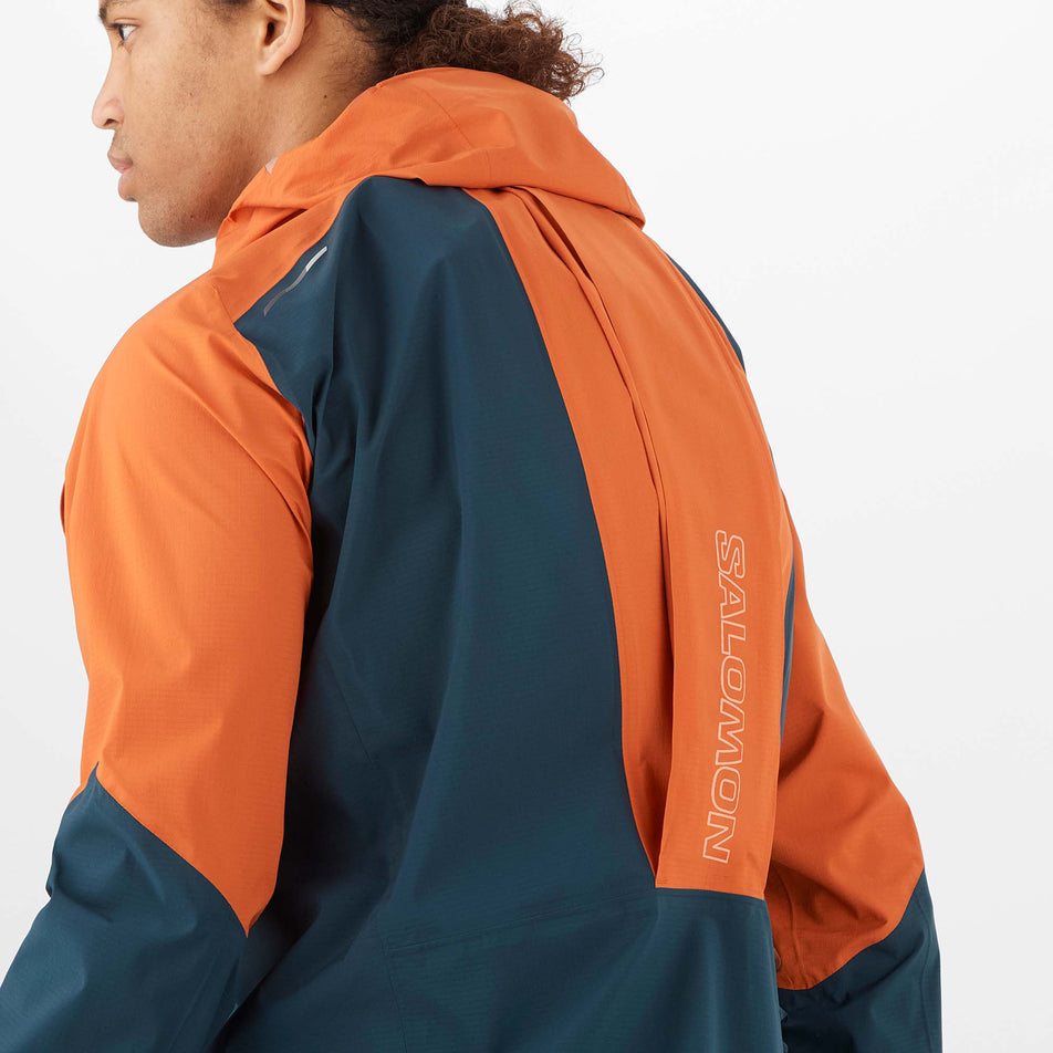 Close-up angled back view of a model wearing a Salomon Men's Bonatti Trail Jacket in the Burnt Ochre/Carbon colourway.   (8008561098914)