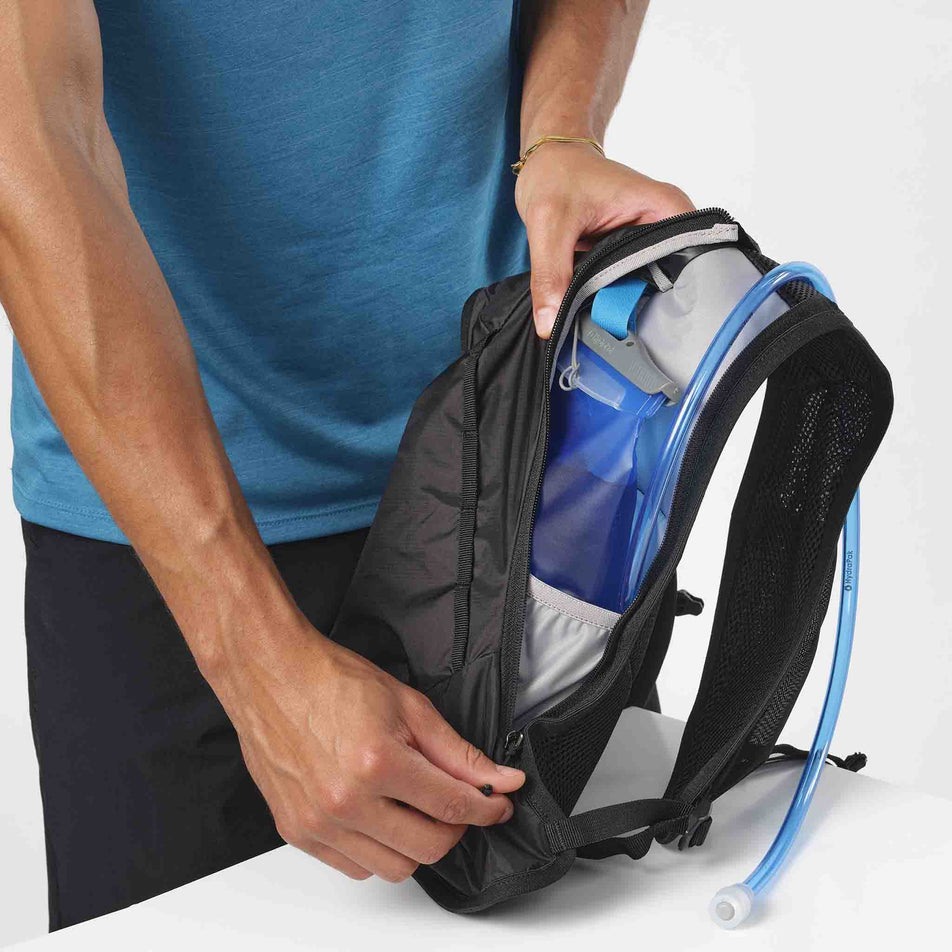 A model demonstrating that a hydration bladder can be stored in a Salomon Unisex Cross 4 Rucksack. (8407394123938)