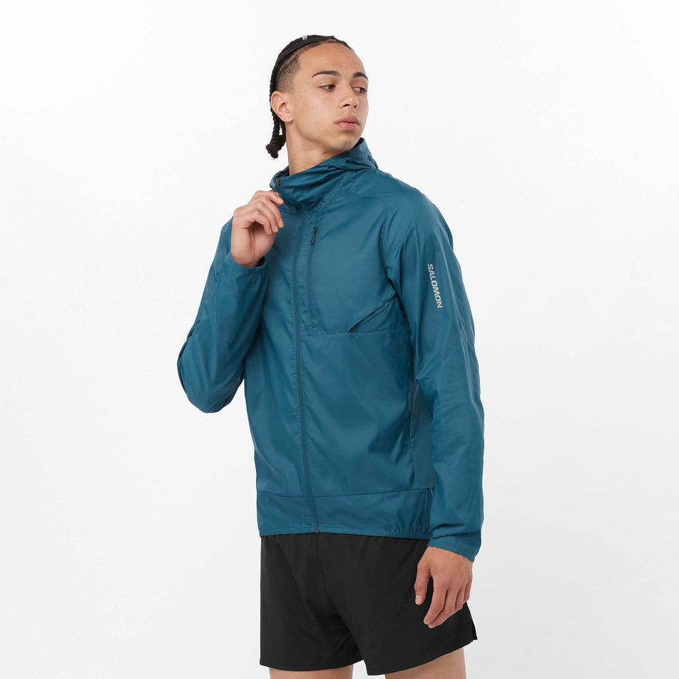 Front view of a model wearing a Salomon Men's Cross Wind Jacket in the Deep Dive colourway. Model is also wearing shorts.  (8157819568290)