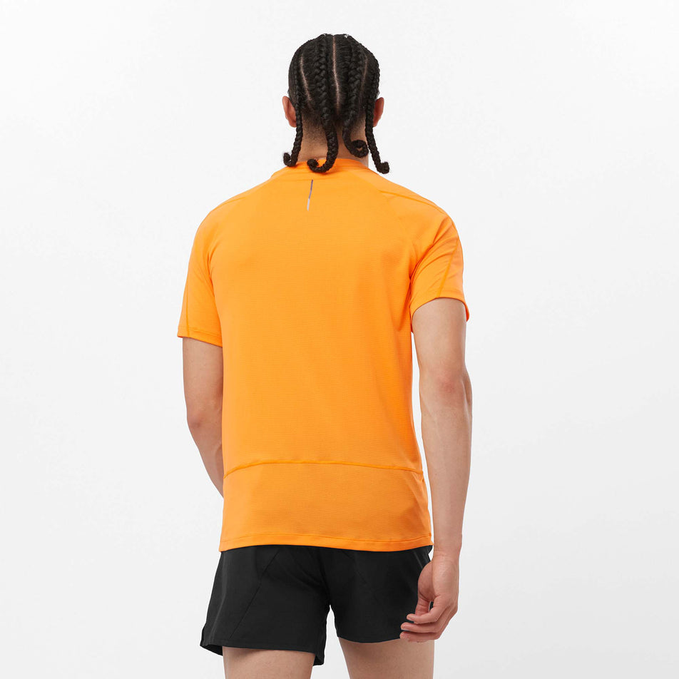 Back view of a model wearing a Salomon Men's Cross Run Short Sleeve T-Shirt in the Zinnia colourway. Model is also wearing shorts. (8157835428002)