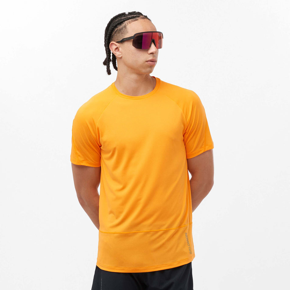 Front view of a model wearing a Salomon Men's Cross Run Short Sleeve T-Shirt in the Zinnia colourway. Model is also wearing legwear and sunglasses. (8157835428002)