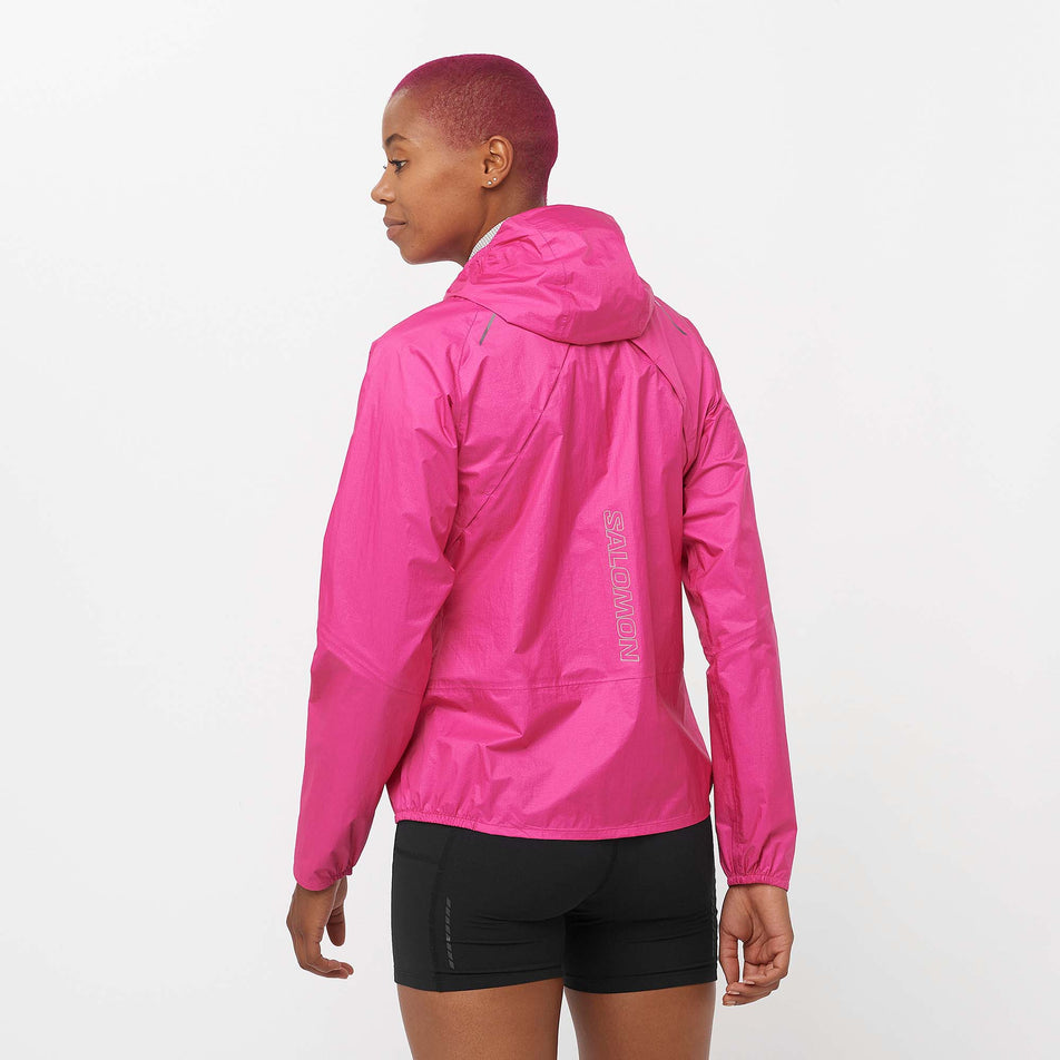 Back view of a model wearing a Salomon Women's Bonatti Waterproof Jacket in the Beetroot Purple colourway. Model is also wearing Salomon shorts. (8157863674018)