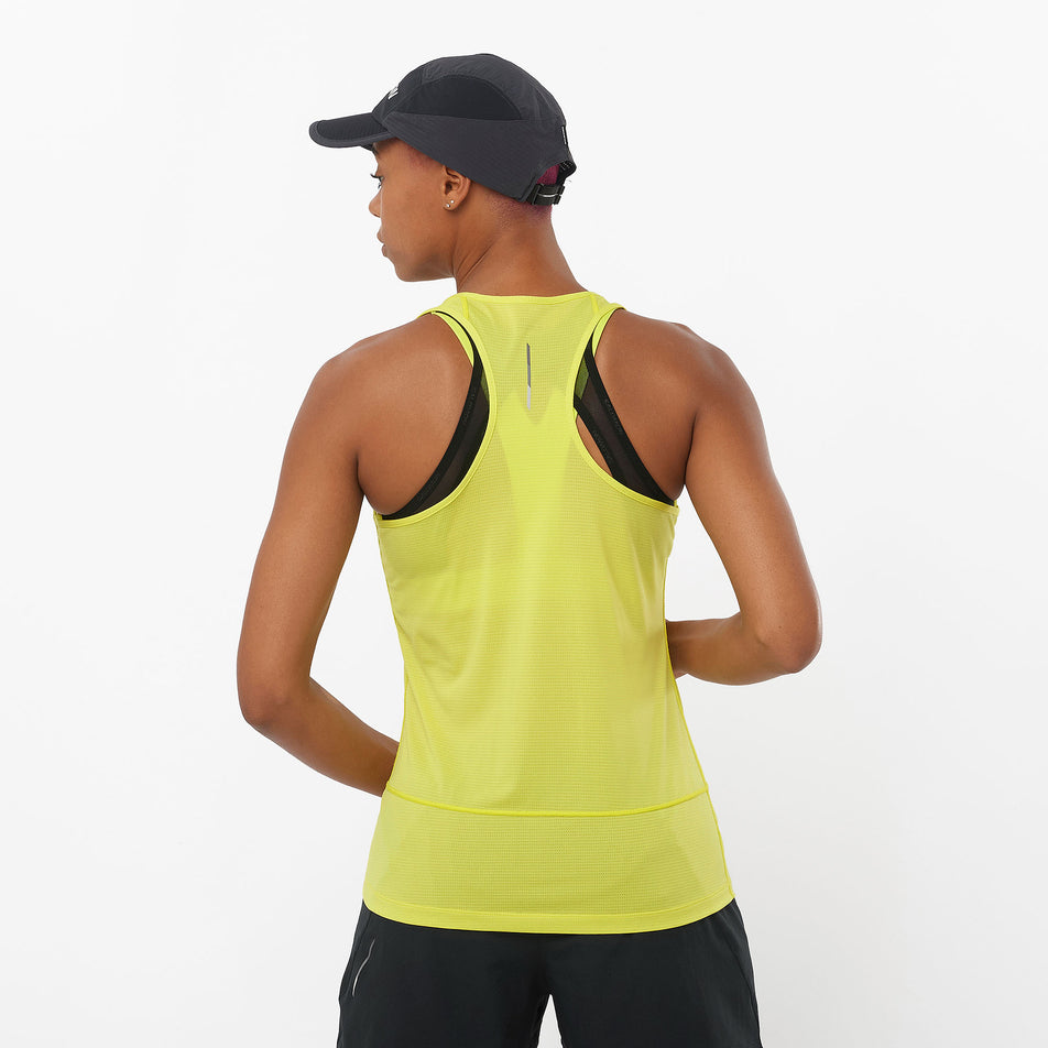 Back view of a model wearing a Salomon Women's Cross Run Tank in the Sulphur Spring colourway. Model is also wearing a Salomon cap and shorts. (8311902896290)