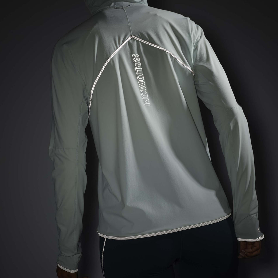 The reflectivity on the back of a Salomon Women's Sense Aero Hybrid Half Zip Midlayer in the Misty Blue colourway. Top is being worn by a model. (8463148417186)