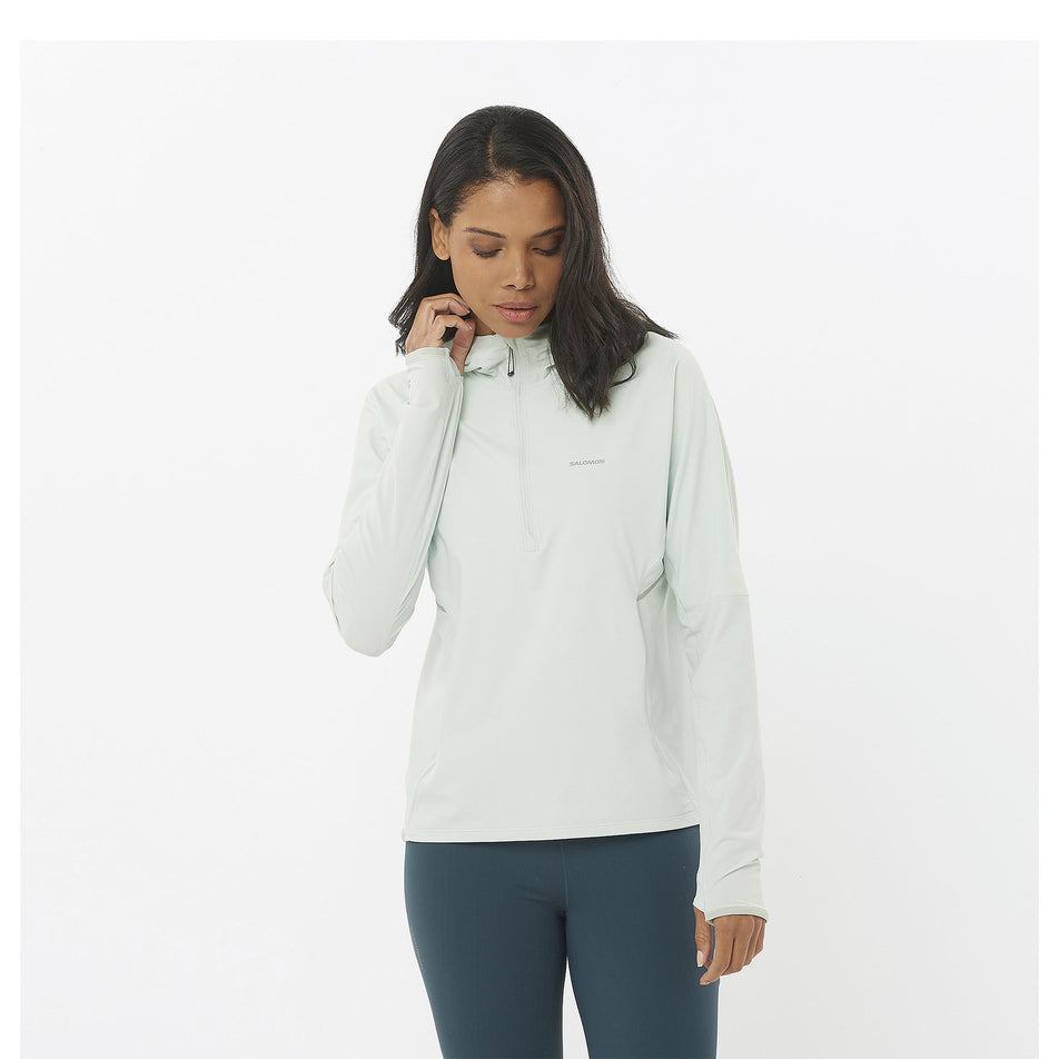 Front view of a model wearing a Salomon Women's Sense Aero Hybrid Half Zip Midlayer in the Misty Blue colourway. Model is also wearing Salomon leggings. (8463148417186)