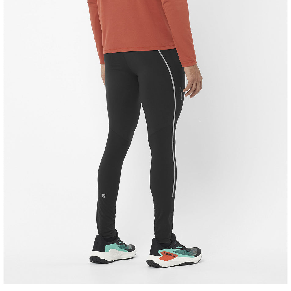 Back view of a model wearing a pair of Salomon Men's Sense Aero Stow Tights in the Deep Black colourway. Model is also wearing a top and Salomon shoes. (8466531057826)