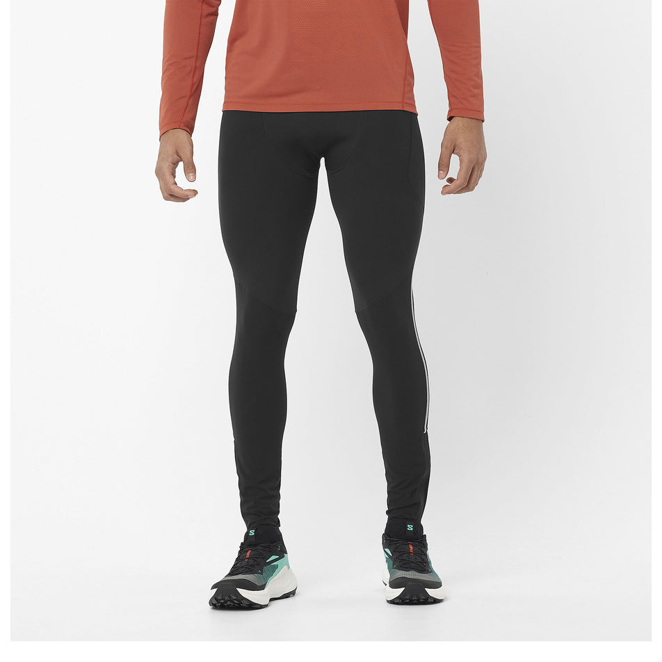 Front view of a model wearing a pair of Salomon Men's Sense Aero Stow Tights in the Deep Black colourway. Model is also wearing a top and Salomon shoes. (8466531057826)