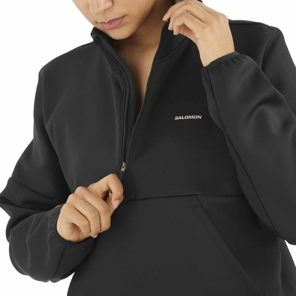 Front view of a model demonstrating the zip on the front of the Salomon Women's SHKout Half Zip Midlayer in the Deep Black colourway. (8575544721570)